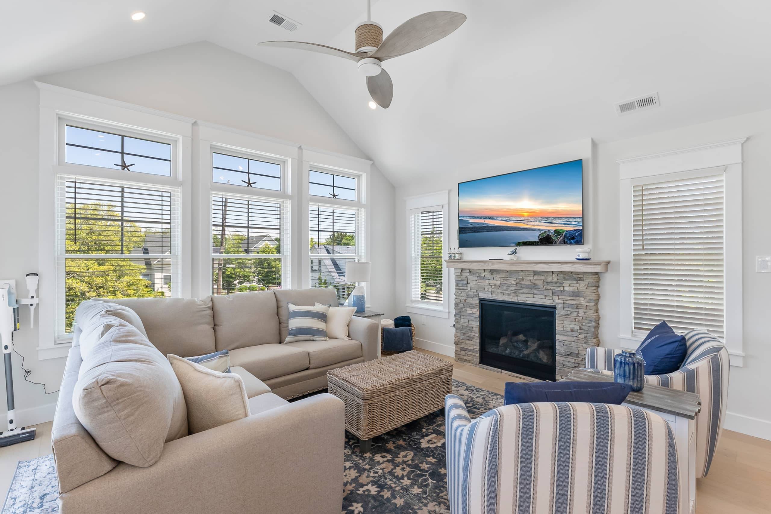 Living room at The Delford with bay windows, a stone fireplace, and striped chairs