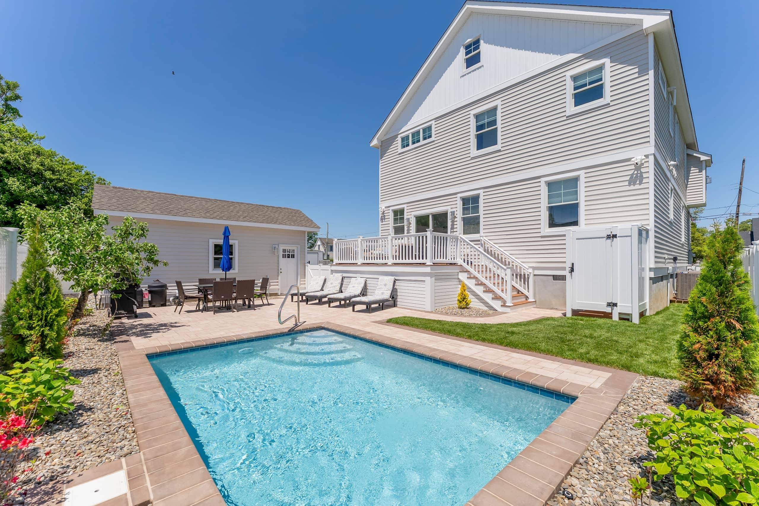 Heated pool, lounge chairs, and outdoor dining in the fenced yard at The Delford